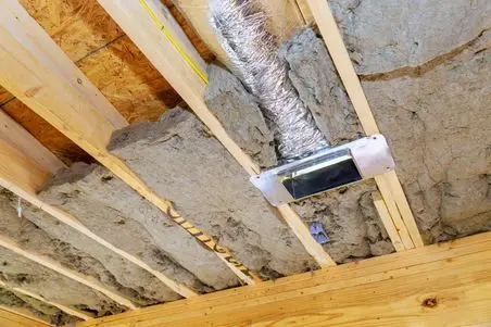 Exposed basement ceiling shows wooden beams, insulation between joists, metal air duct, and wiring. Unfinished construction with visible yellow wire and reflective ductwork.