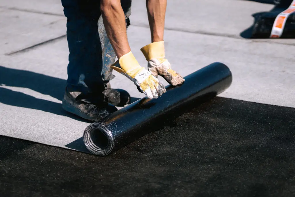 roofing membrane. Professional workers waterproofing house construction site. Worker rolling membrane