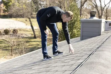 roof inspection wisconsin guy inspecting grey shingles roof