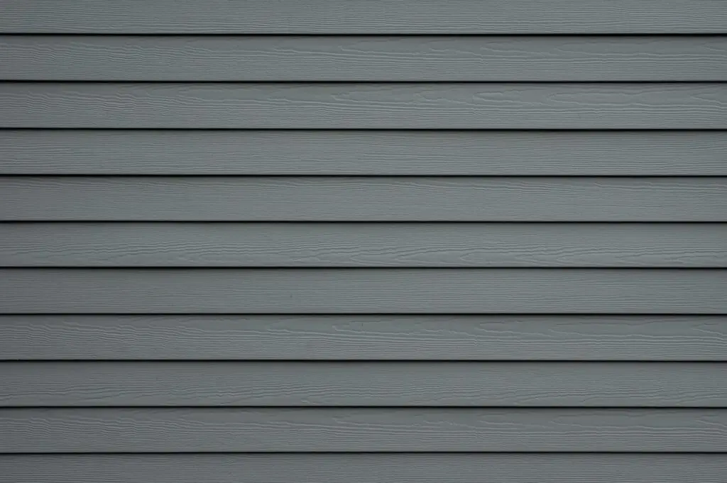 Gray horizontal vinyl siding with a woodgrain texture, evenly spaced and covering the entire image. The surface looks clean and uniform, commonly seen on the exterior of houses.