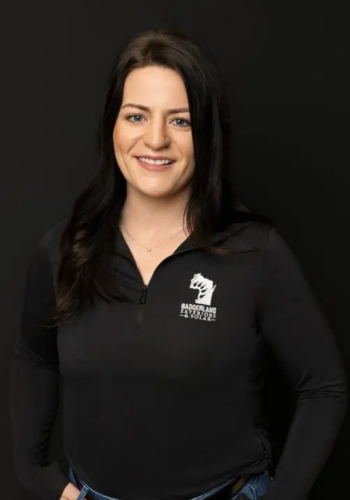 A woman with long dark hair, wearing a black zip-up shirt with the 