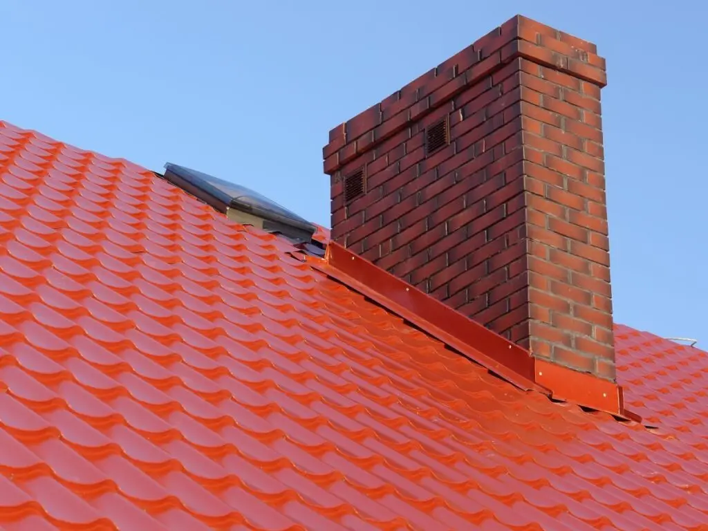 red metal tile roof with a brick chimney and chimney flashing