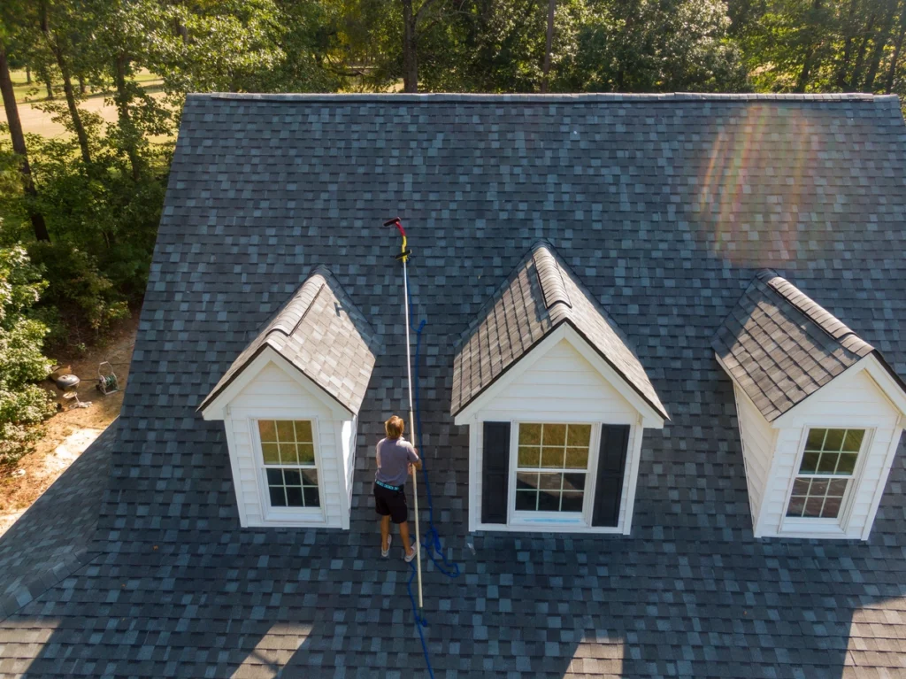 person cleaning their asphalt shingles