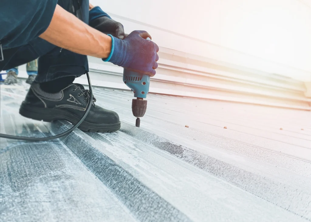 commercial roofing stoughton worker drilling in metal roofing commercial building