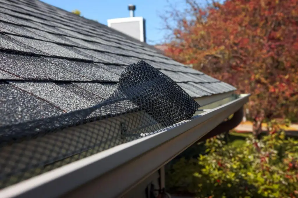 Black mesh gutter guard installed on the edge of a shingled roof.