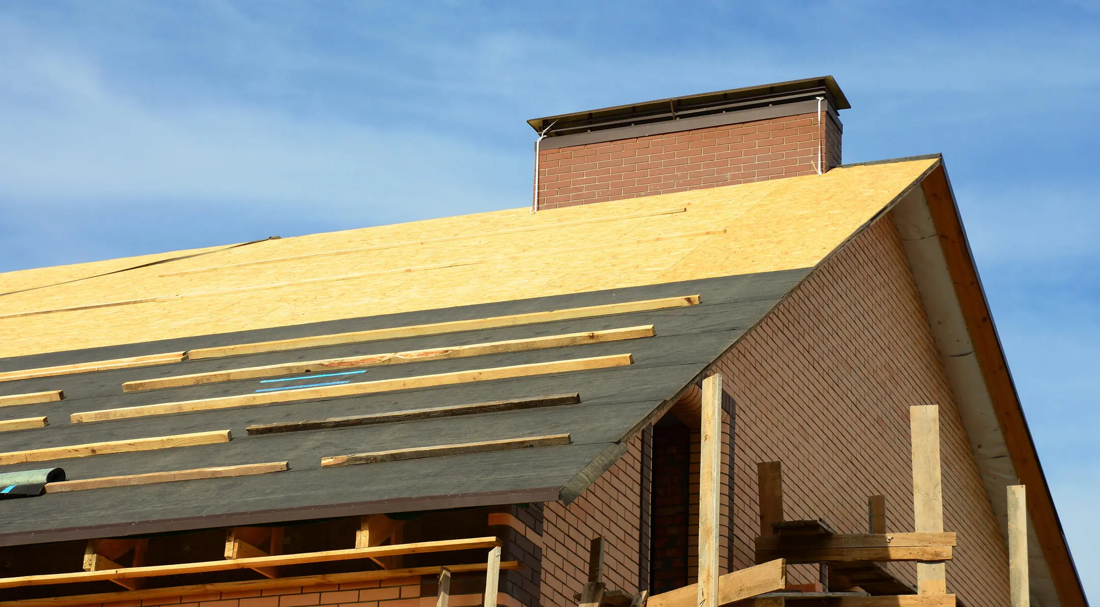 roof decking-roof replacement on a brick house with roof sheathing and underlayment exposed