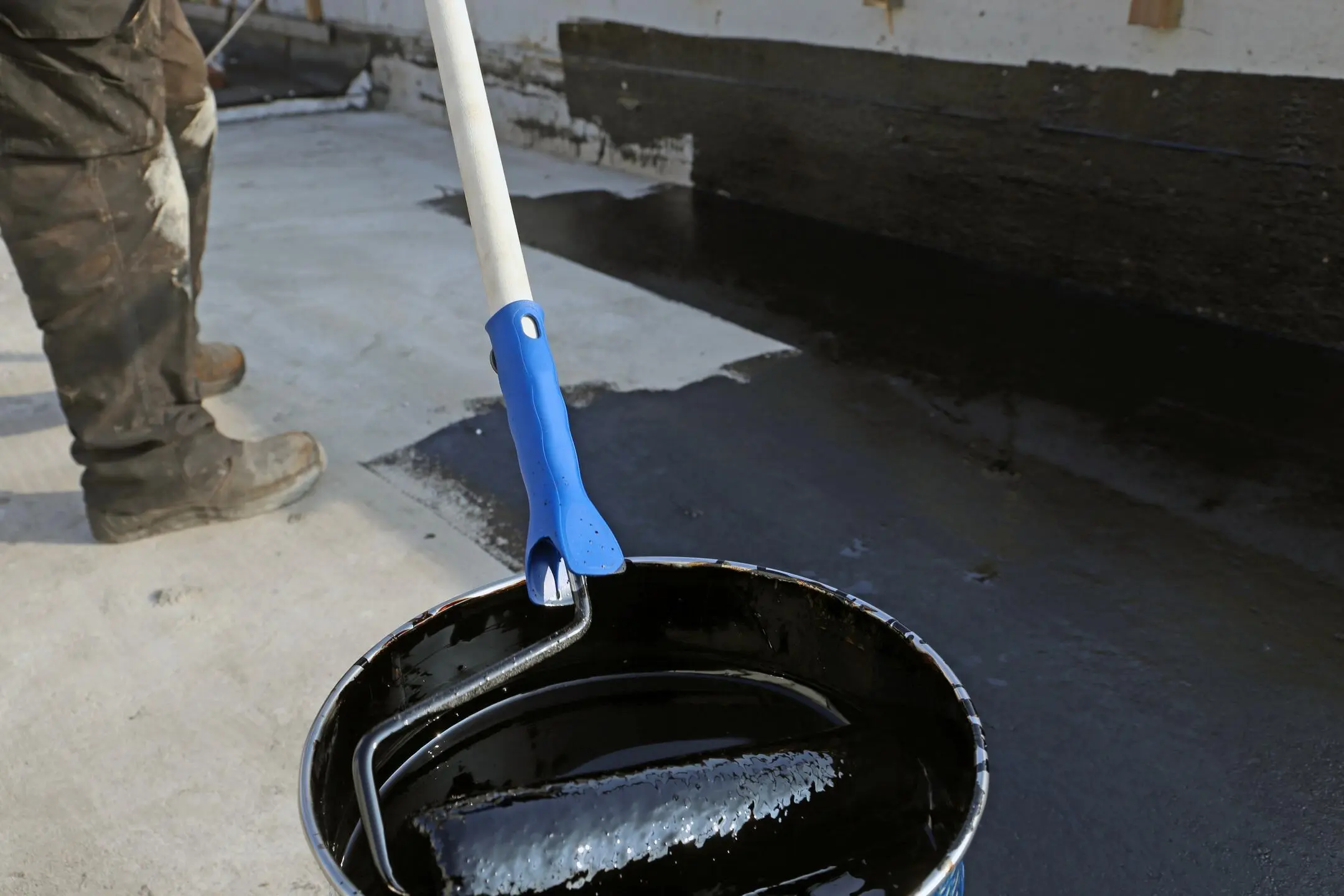 roof coating-close up of paint roller in black coating material