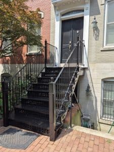 Elegant black metal staircase with railings to a front door.