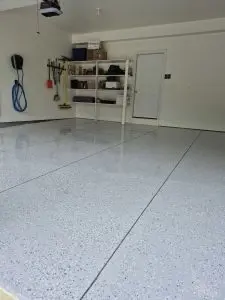 Garage floor epoxy coating with organized storage shelves and tools in a clean, modern garage space.