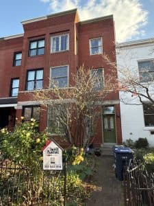 Red brick townhouse with large windows and a small front garden.