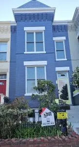 Colorful blue Victorian house with white trim and large windows.