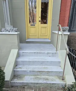 Front entrance with yellow door and concrete stairs, residential building exterior.