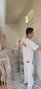 Professional interior wall painting in progress with painter applying fresh paint.