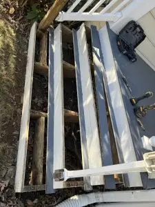Wooden deck framing with metal supports under construction outdoors.