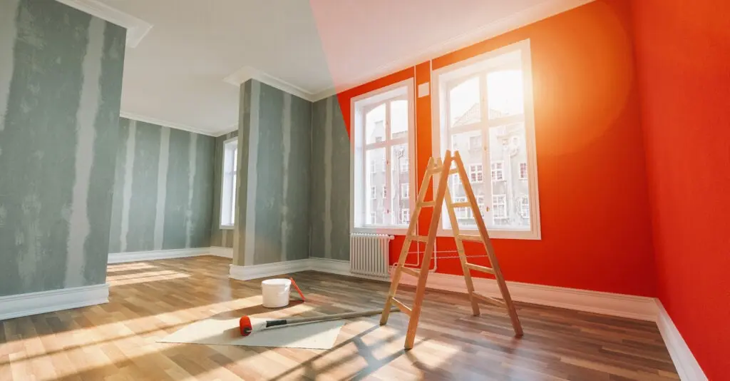 Brightly painted living room with orange and green walls, natural light, and painting tools.