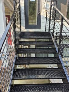 Outdoor metal staircase with safety railings and textured steps for slip resistance.