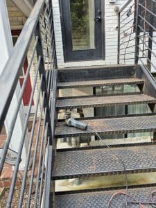 Industrial metal staircase with safety railings and a door in the background.