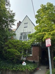 Beautiful vintage house surrounded by lush trees and shrubs.