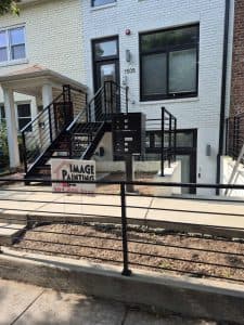 Exterior house painting with modern black railings and stairs.