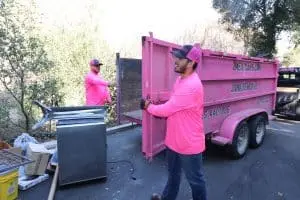 Two Mexicans junk removal team clearing unwanted clutter from a residential property in California for a cleaner space.
