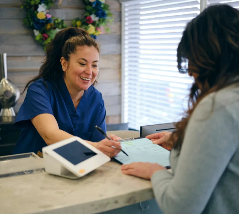 Front desk employee helping a patient with check in paperwork
