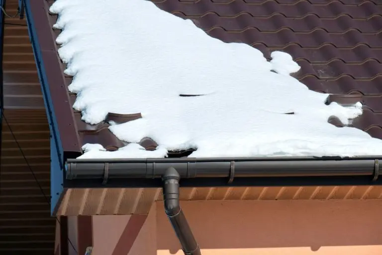 Closeup of house roof top covered with snow in cold winter. Tiled covering of building in wintertime weather