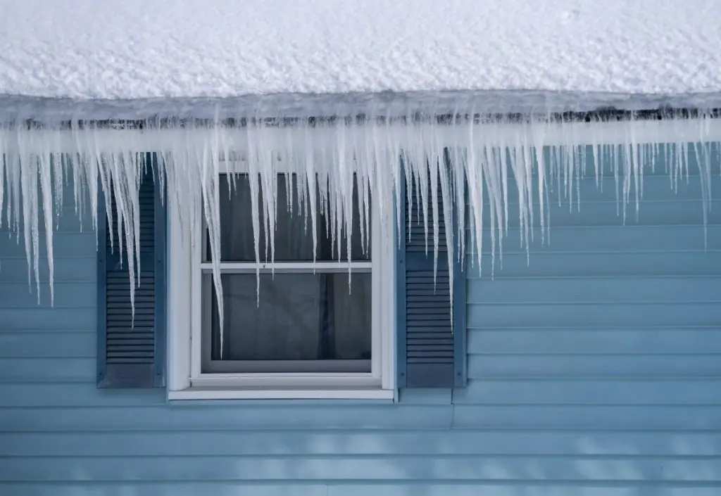winter house with ice dam and snow on the roof