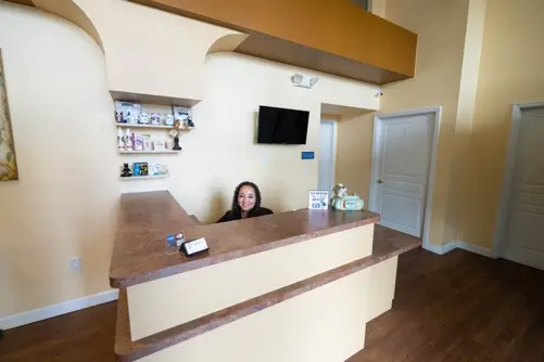 A smiling receptionist seated behind the front desk in the welcoming reception area of Harbourside Animal Hospital.