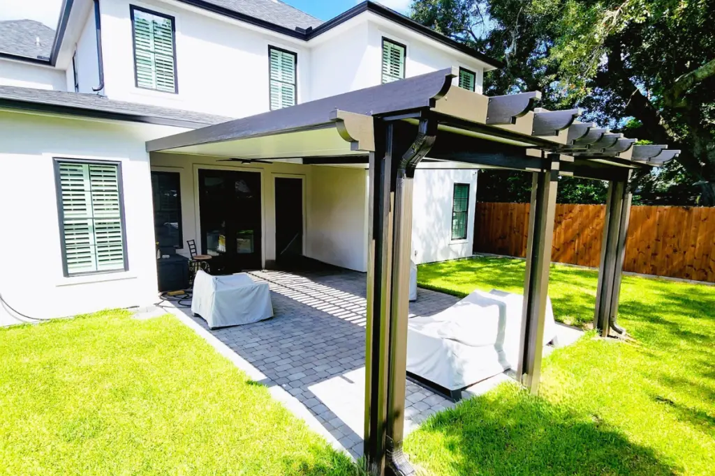 Patio cover featuring insulated roof panels and elegant lattice design, providing shade and protection in a residential outdoor setting with green grass and paver stones.