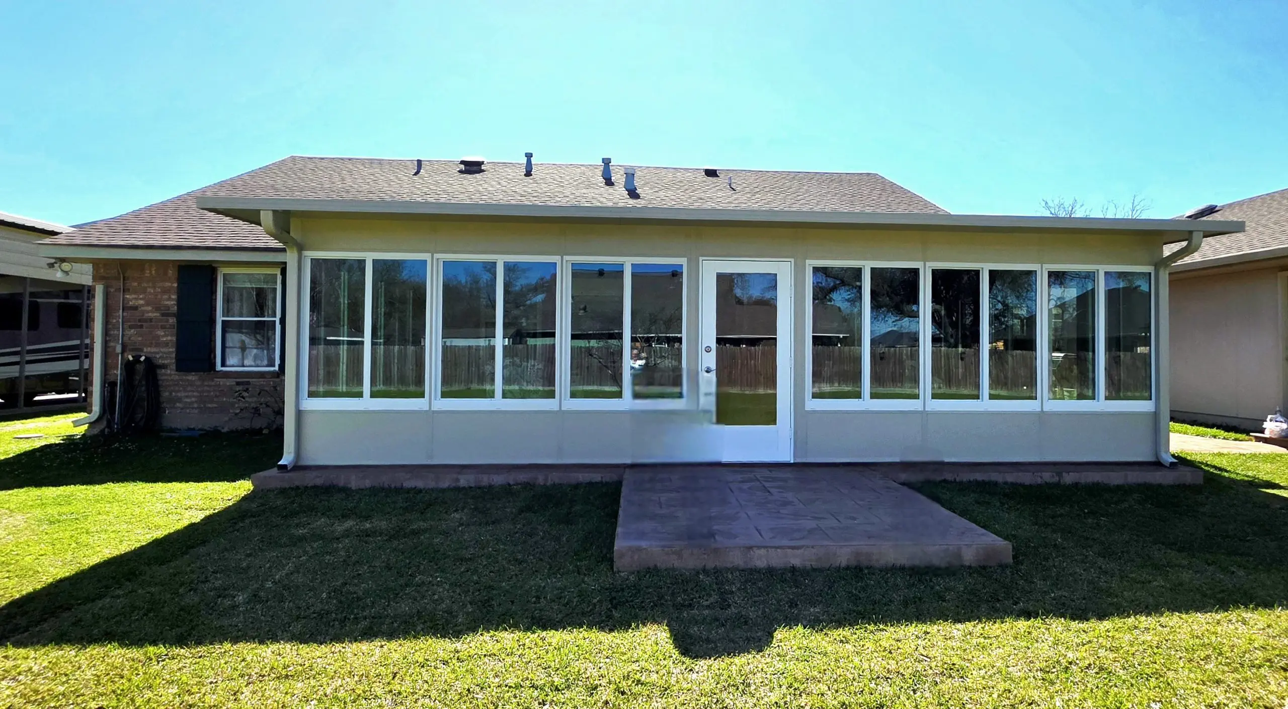 Insulated sunroom with large glass windows and a concrete patio, designed for comfort in New Orleans' subtropical climate.