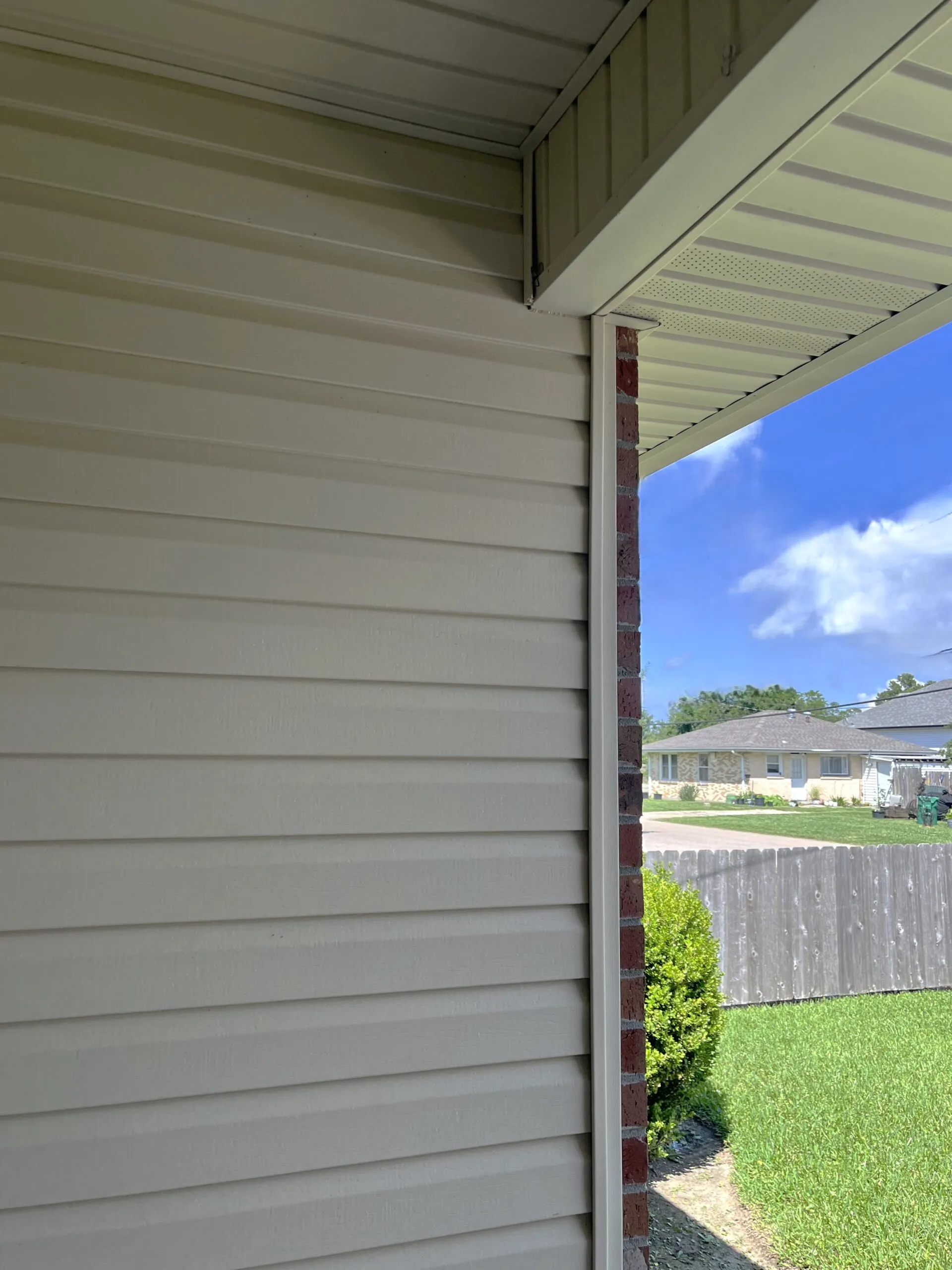 Vinyl siding installation showcasing a seamless finish, complemented by aluminum soffit and brick accents, enhancing curb appeal in a residential setting.