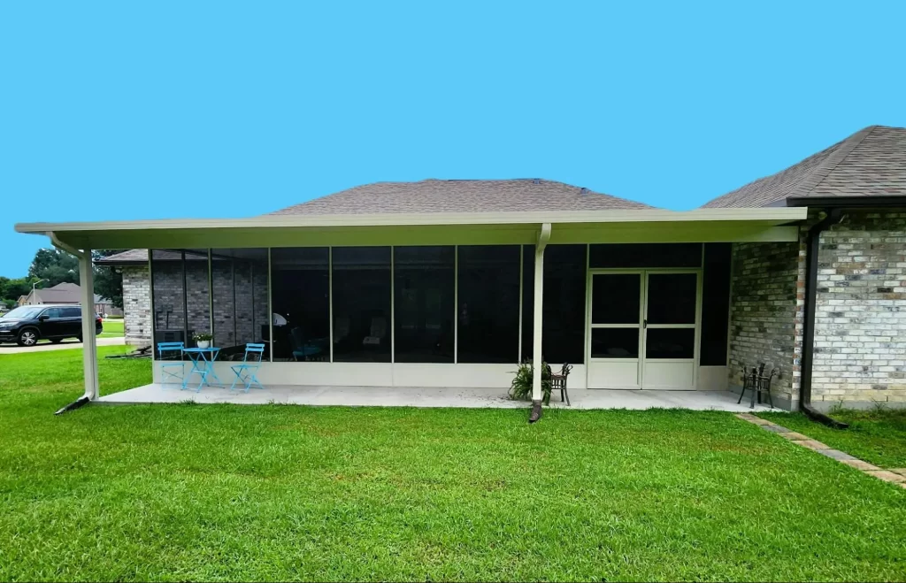 Insulated patio cover enhancing outdoor living space, featuring blue sky backdrop, green lawn, and patio furniture in Greater New Orleans home.