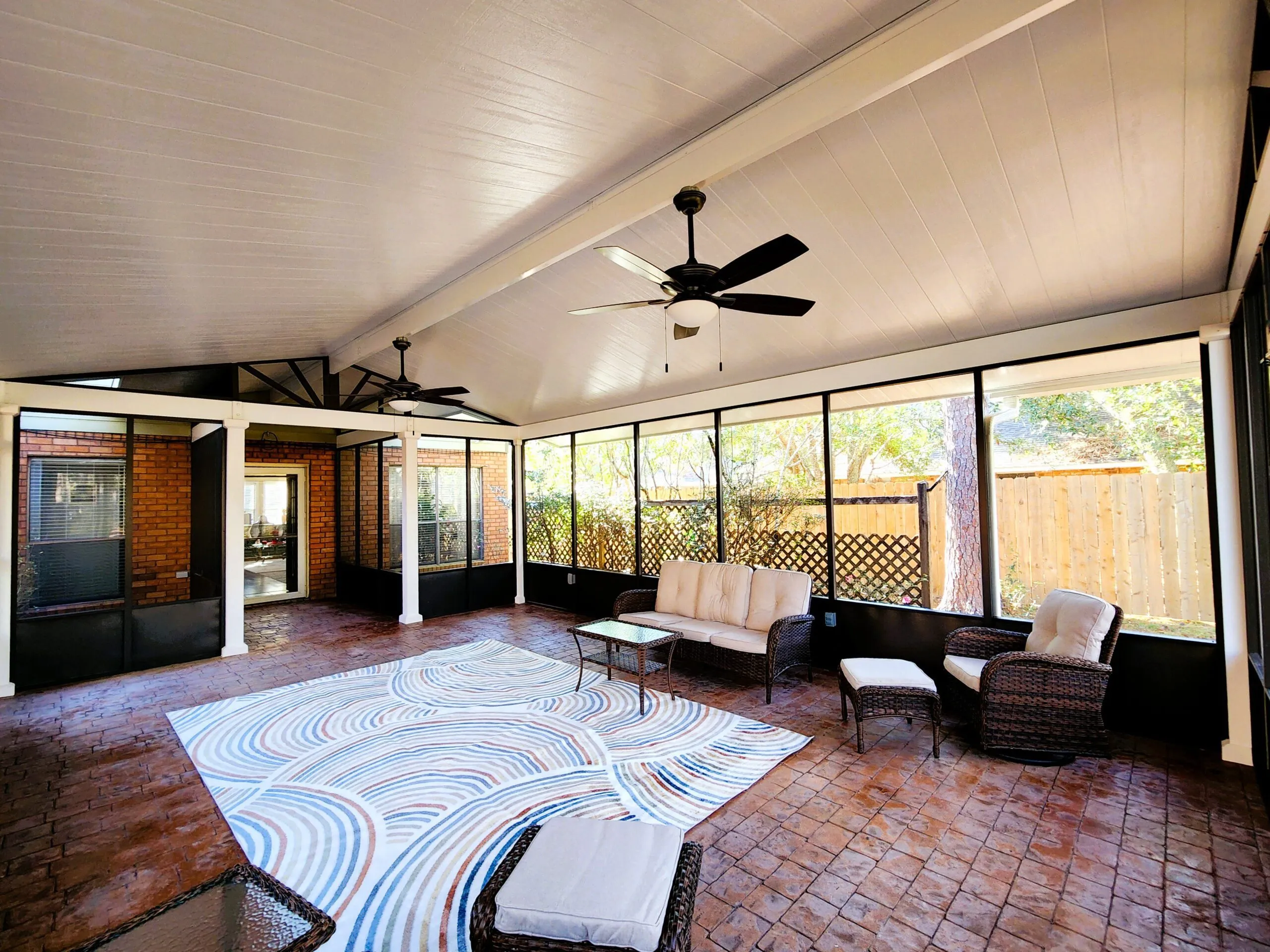 Freestanding bronze screen room with cedar-embossed white insulated patio cover, gabled roof, terracotta stamped concrete flooring, and stylish outdoor furniture in Slidell, LA.