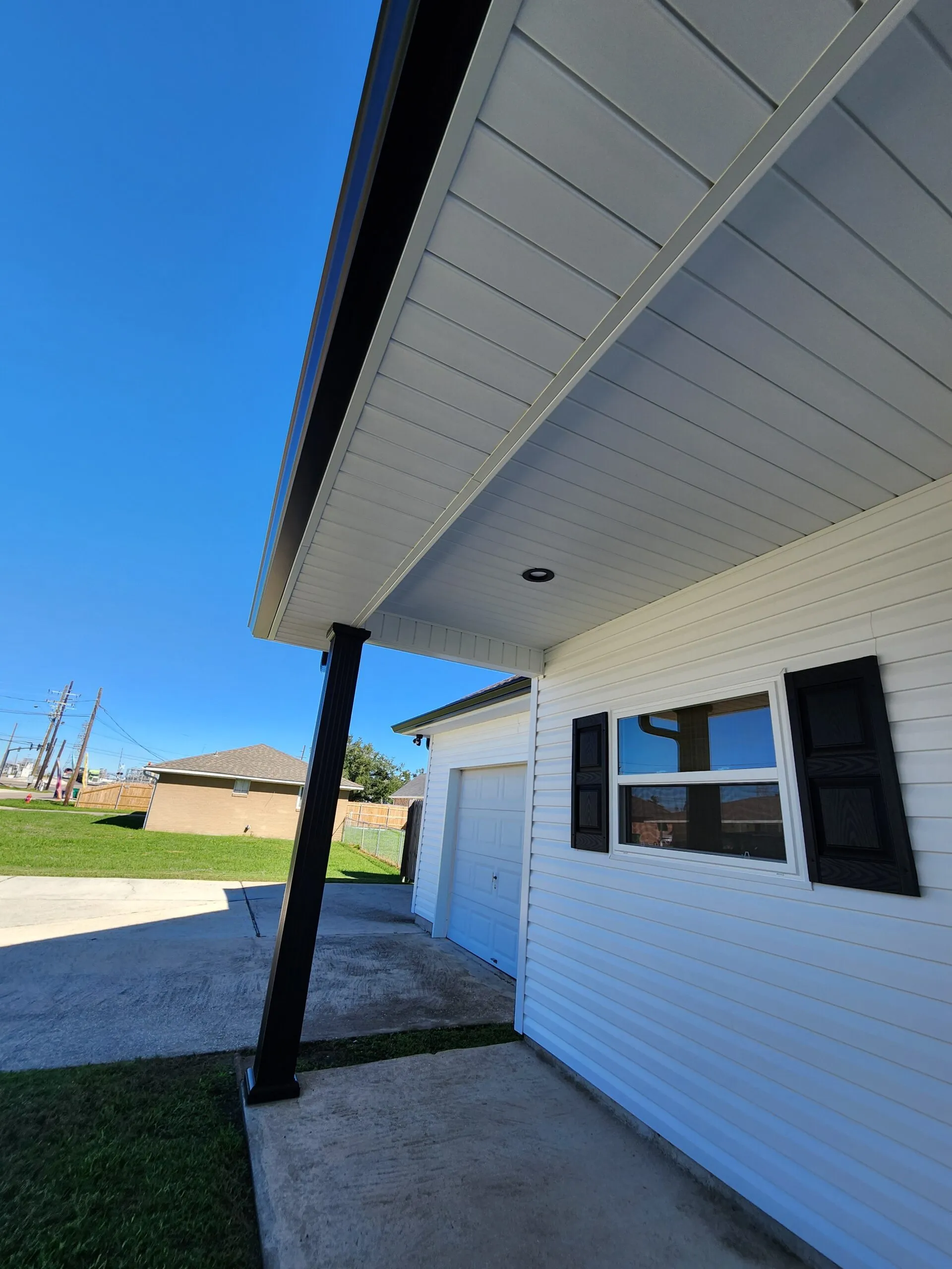 Seamless aluminum gutters installed on a home's exterior, showcasing professional craftsmanship and protection against water intrusion, with a clear blue sky in the background.