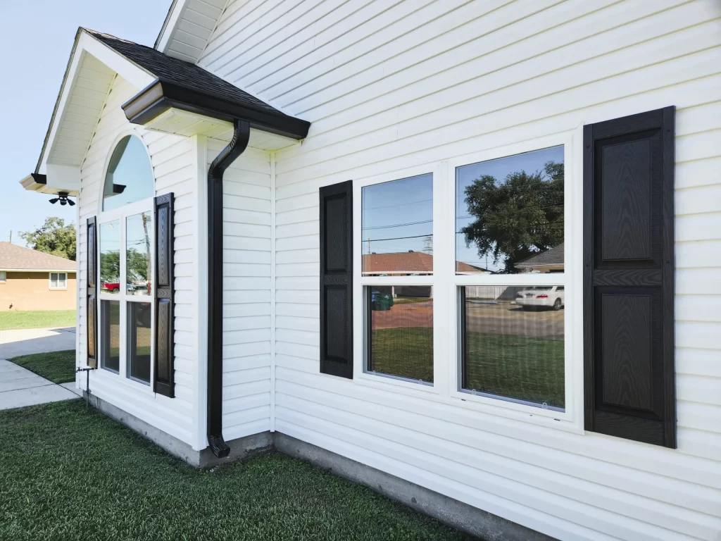 Vinyl siding installation on a Metairie home featuring black shutters, enhancing curb appeal and exterior aesthetics.