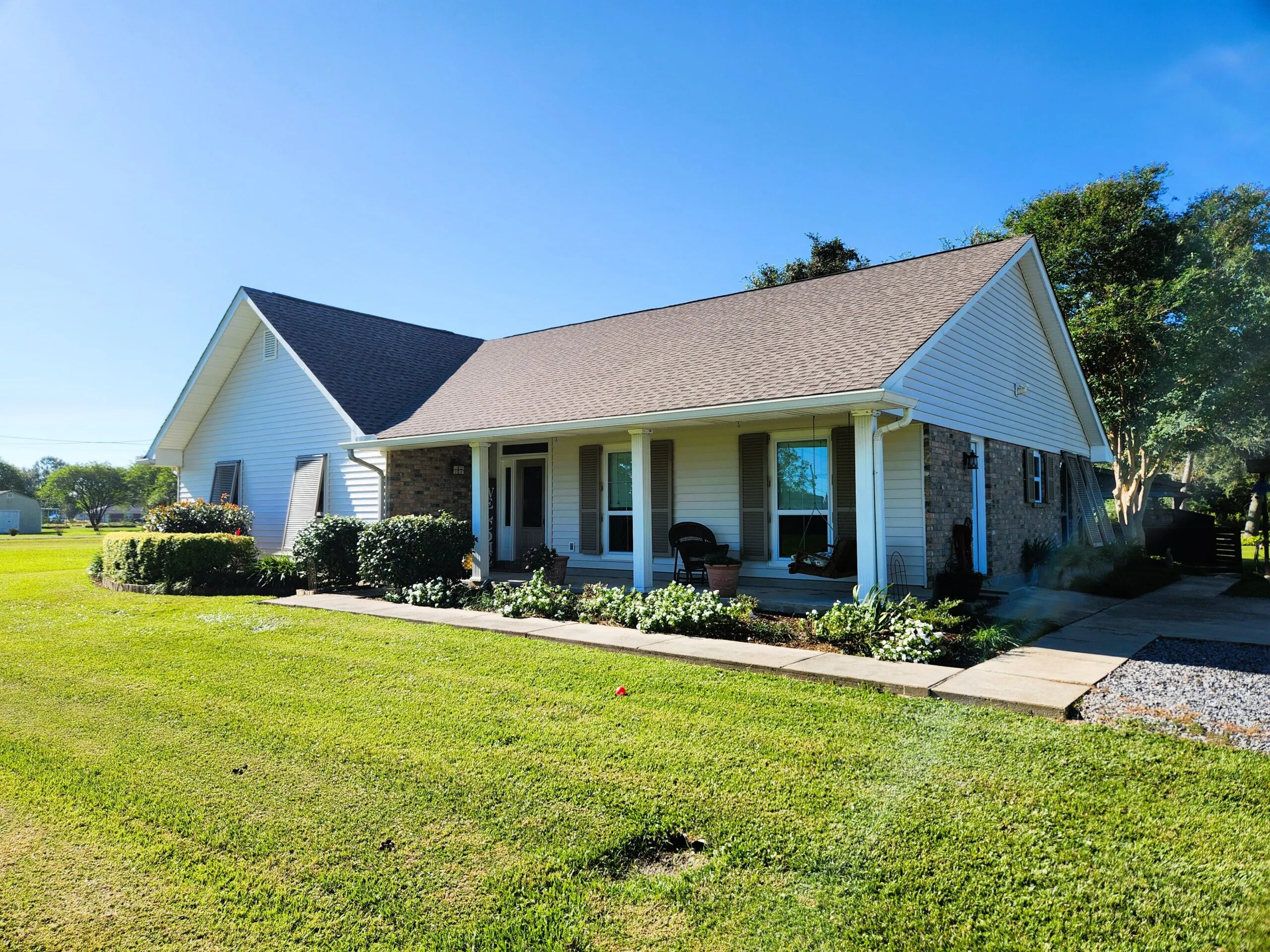 Residential home in Hahnville, Louisiana featuring new Antique White ProVia vinyl siding, white vinyl-coated aluminum fascia, and landscaped front yard.