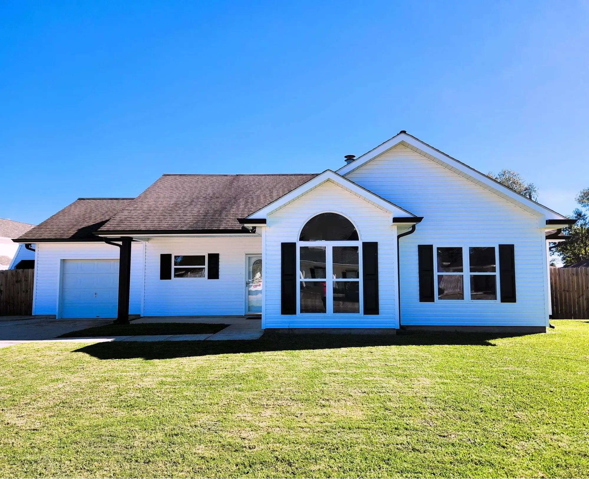 Modern white house with black shutters and a gabled roof, showcasing durable siding suitable for hurricane-prone areas in Louisiana.