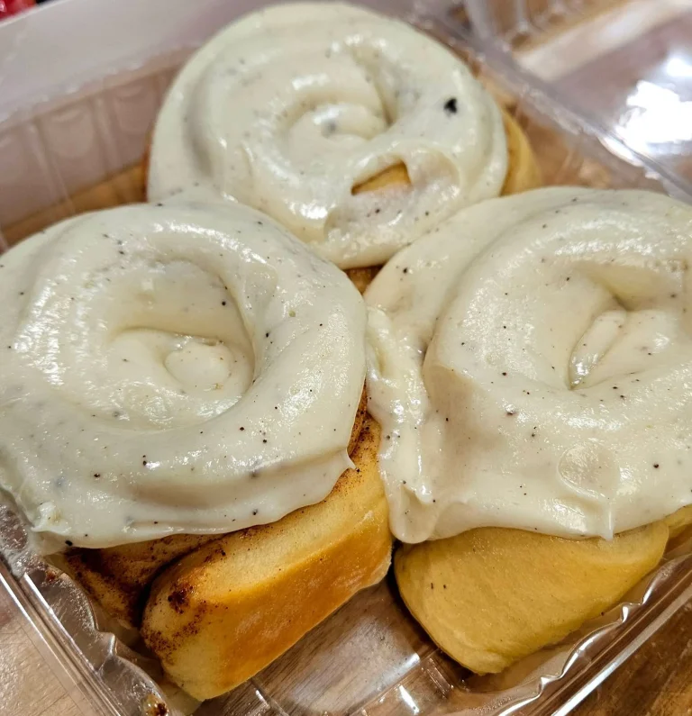 Whipped Creamery, Martinez, GA: close-up of three iced cinnamon rolls with thick white cream cheese frosting in a clear plastic takeout container
