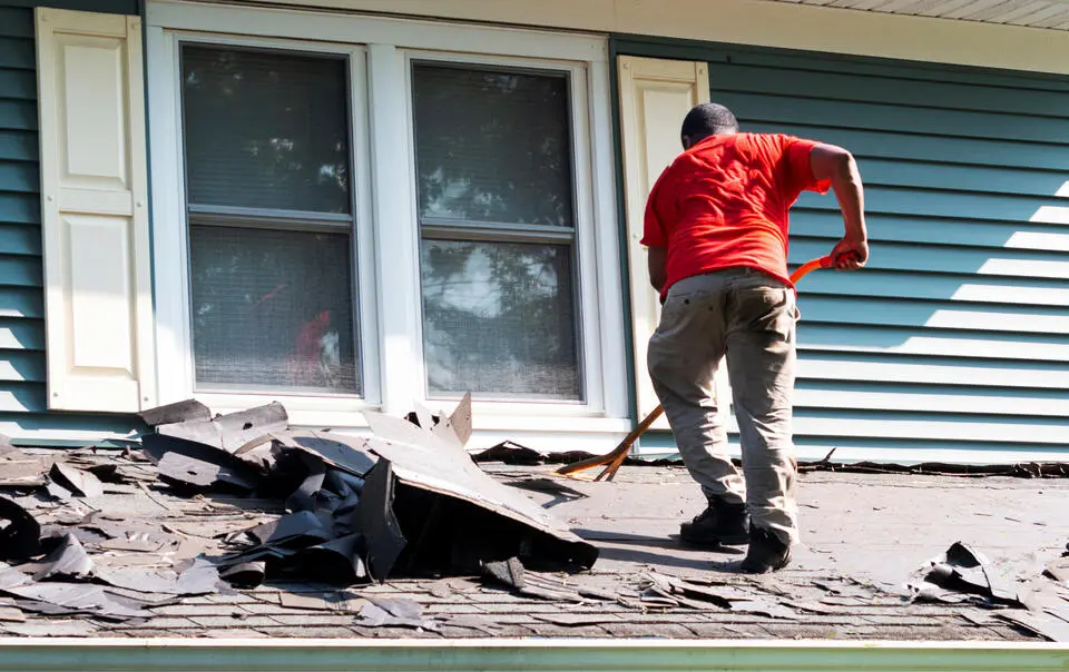 roof installation-man removing old roofing materials