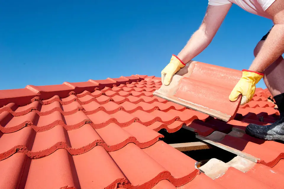 tile vs shingle roof-roofer installing new tile roofing on a house