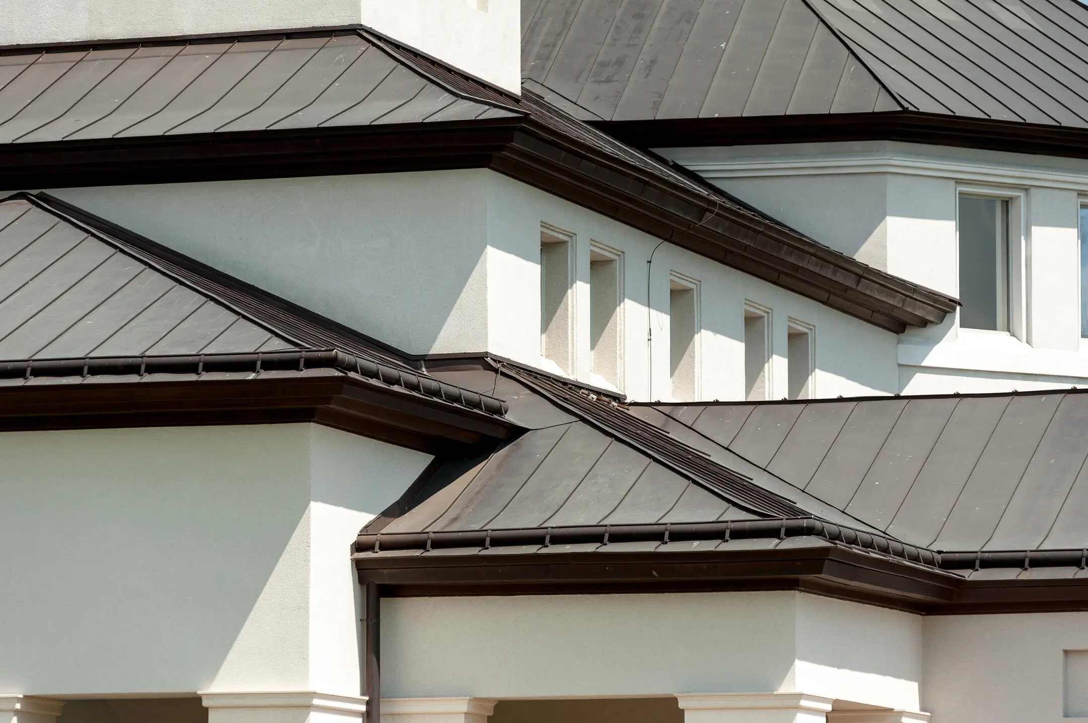 energy efficient roofing-dark standing seam metal roofing on white sided house