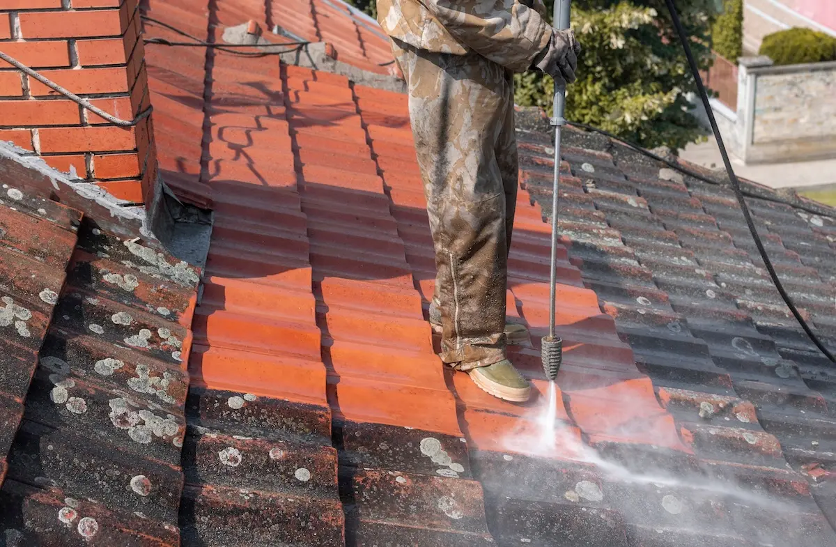 State of roof before and after washing with high pressure. Professional is wearing uniform and using equipment for cleaning.