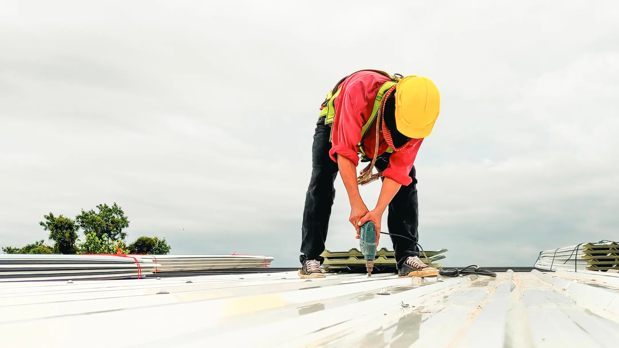 commercial roof replacement-roofer in safety gear installing new metal roofing