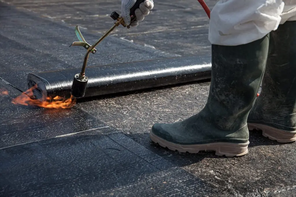 worker overlay the roofing material on the flat concrete surface