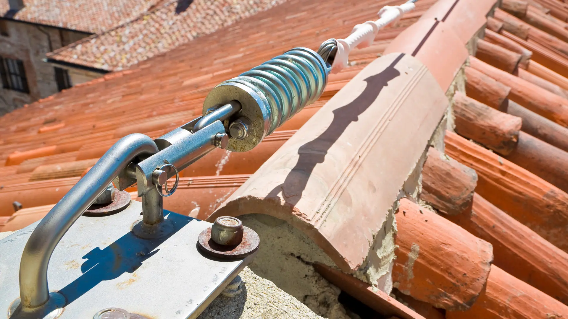 Roofing safety equipment featuring a tensioning device and safety line on a tiled roof, illustrating fall protection measures relevant to OSHA regulations in the roofing industry.