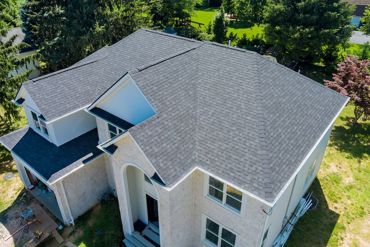 Gray asphalt shingles on a stone house in Elk River, MN, showcasing roofing quality relevant to Owl Roofing's services.