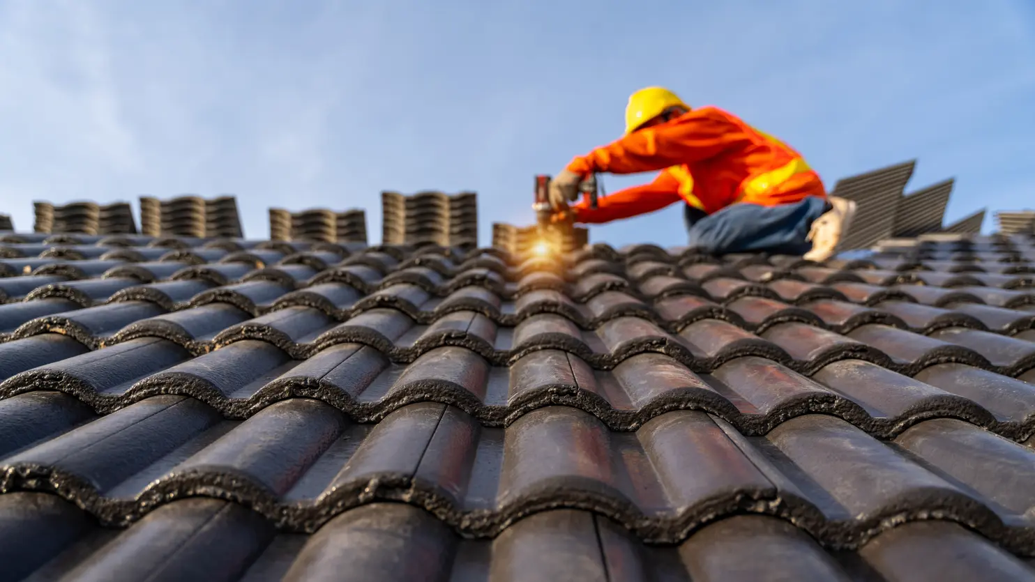 Construction worker in safety gear installing roofing tiles, demonstrating proper material handling and electrical safety practices in roofing work.