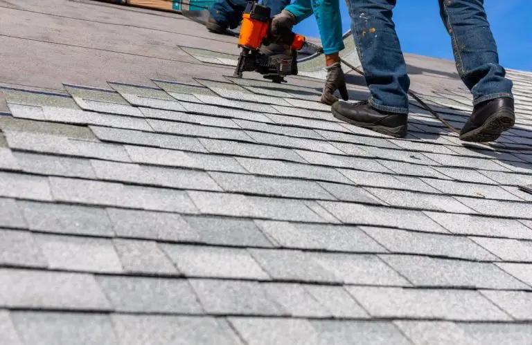 Roofer installing roof shingles with nail gun on a Woodbury home