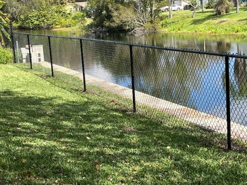 Black vinyl-coated chain link fence installation along a Tampa waterfront