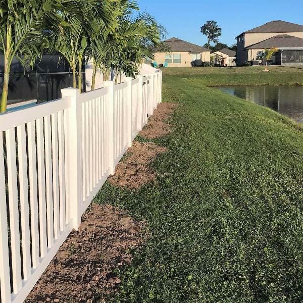Installed tan vinyl semi-privacy picket fence along a residential lakefront property line in Tampa